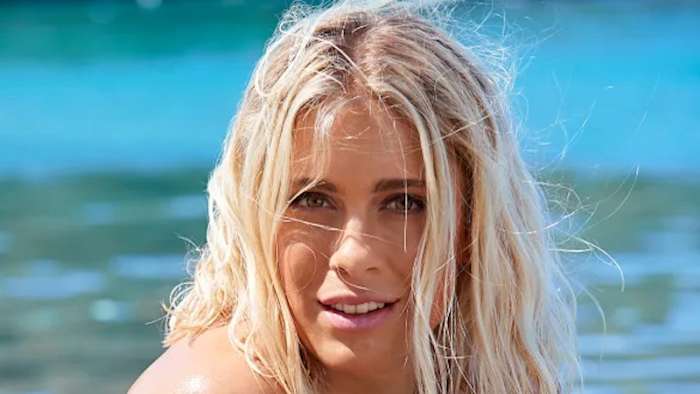Abby Dahlkemper poses in front of the vibrant green-blue ocean water.